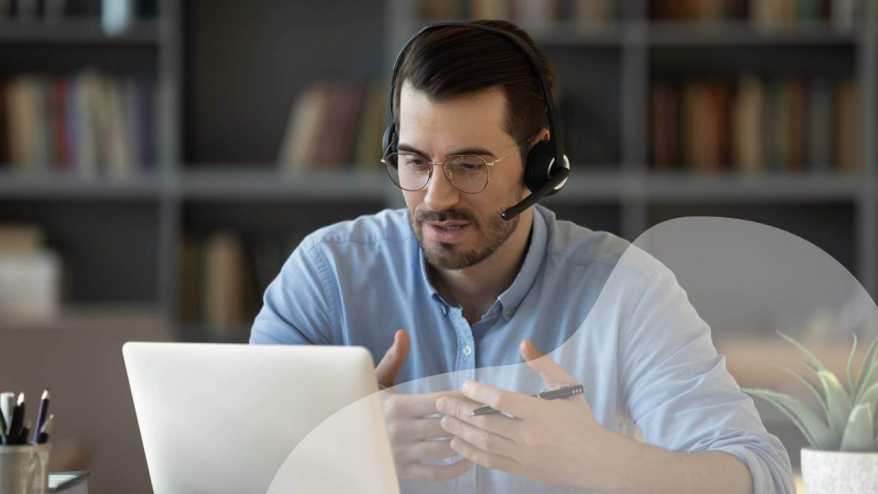 A worker speaks through a headset during an online meeting