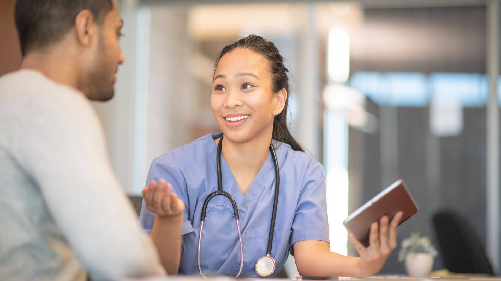 doctor holding tablet speaking with patient