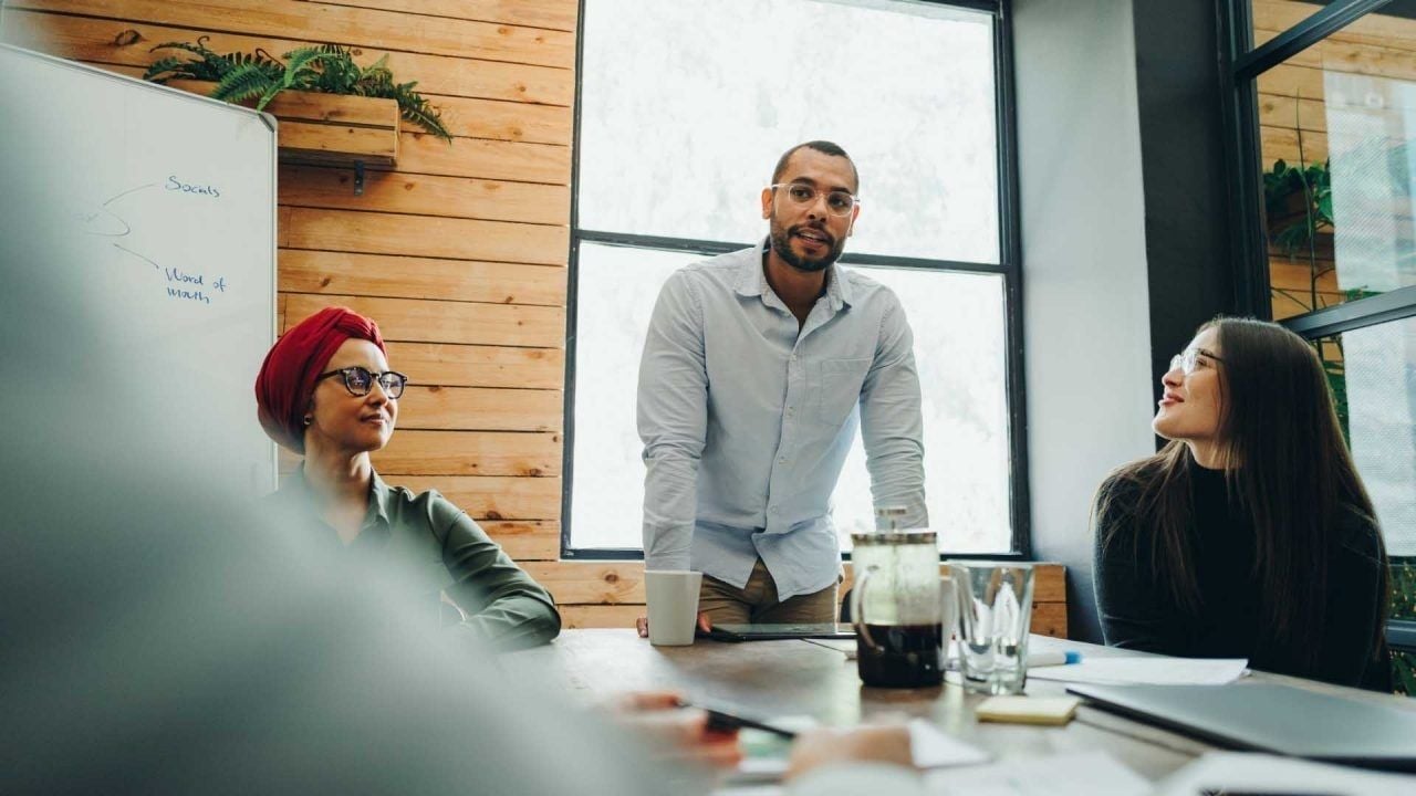man leading a meeting in an office surrounded by coworkers