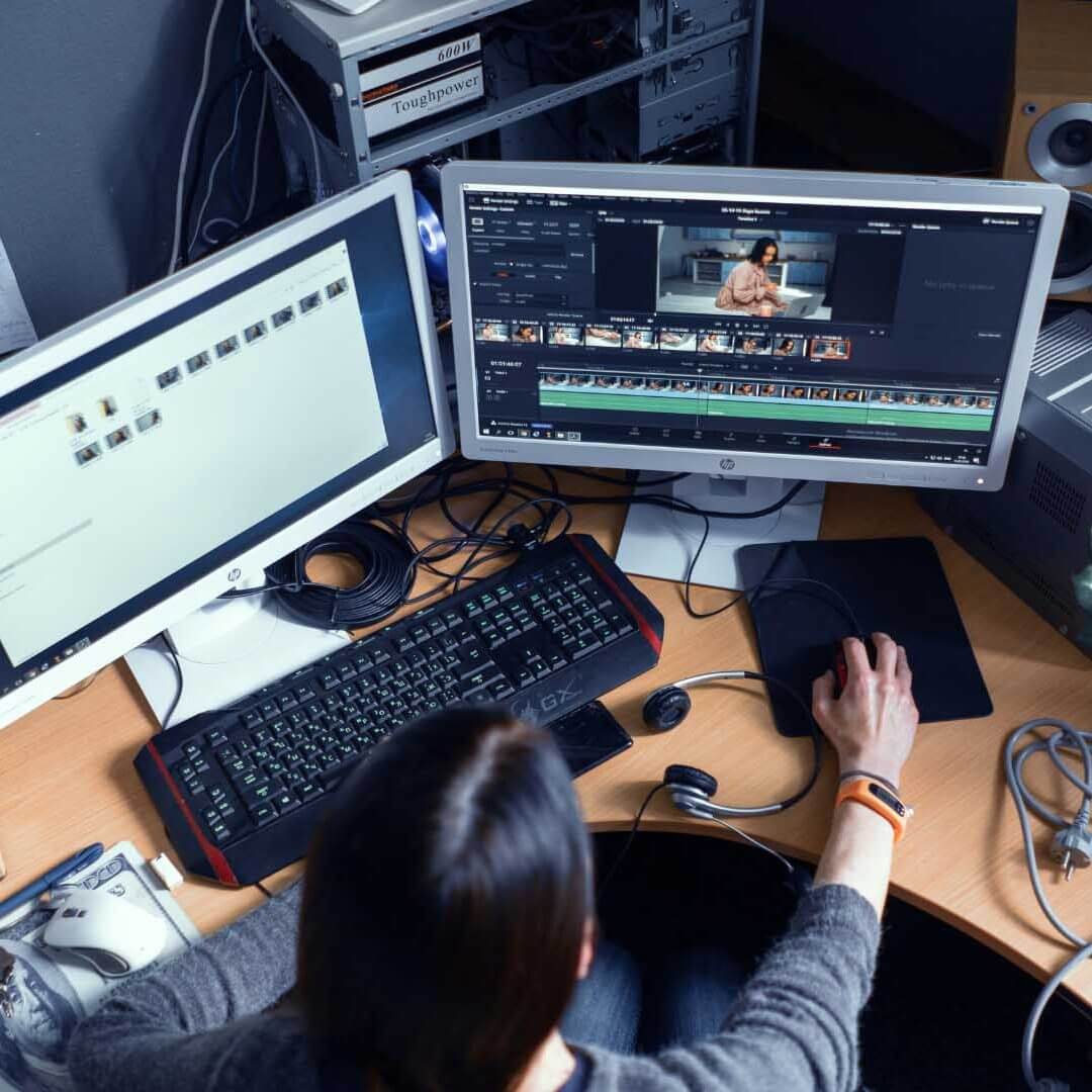 person editing video on two monitors