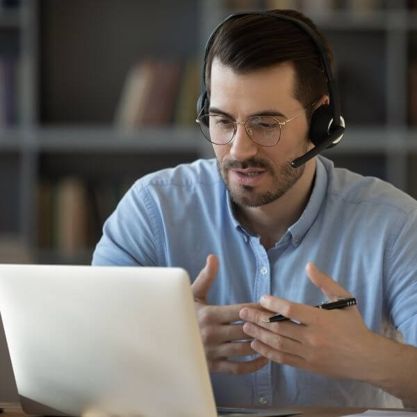 Business man speaking into a laptop with a headset