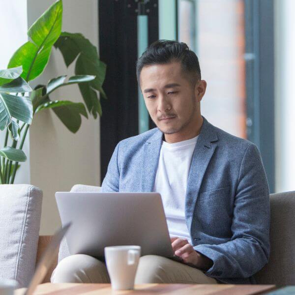 man sitting on couch working on laptop