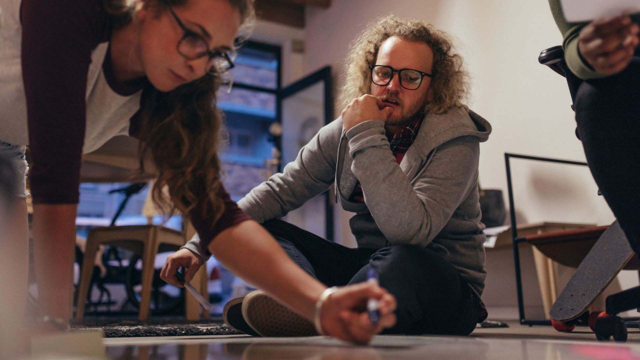 Two people working collaborating writing on the floor