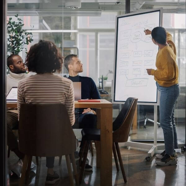 coworkers brainstorming a business plan on a whiteboard in meeting room coworkers brainstorming a business plan on a whiteboard in meeting room