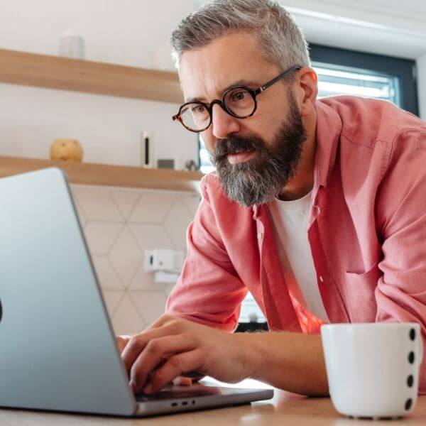 man in pink shirt working from home with coffee