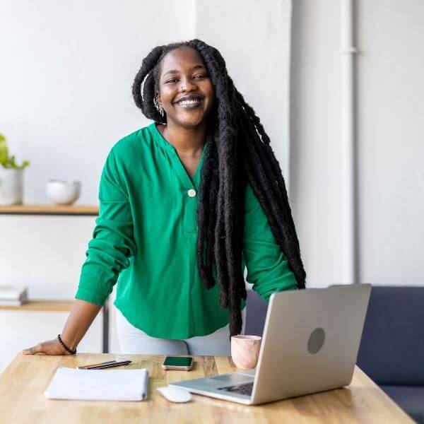 woman standing in green shirt at a desk with laptop