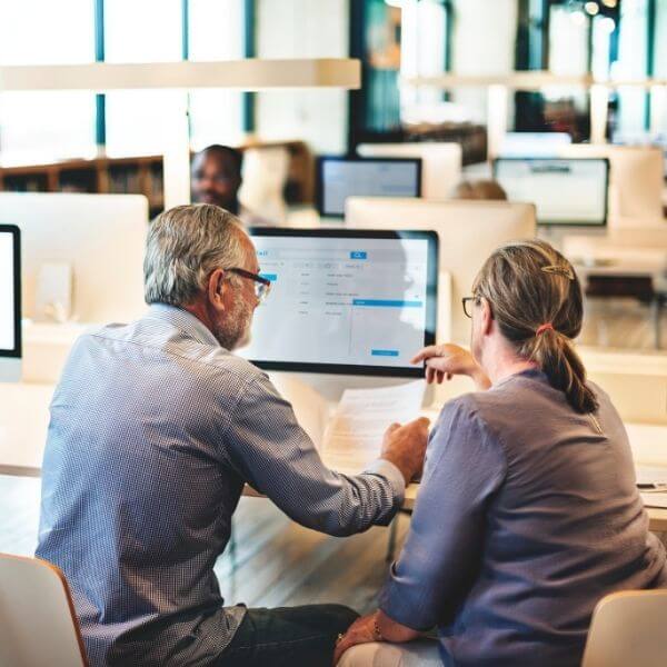co-workers at a desk reviewing documents in front of their computers