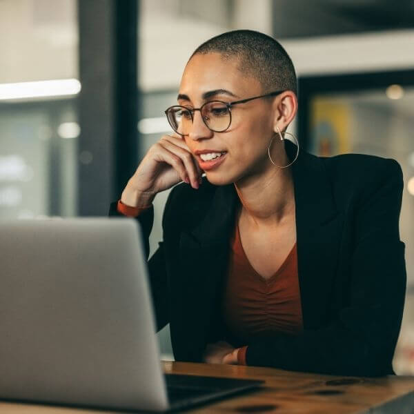 woman in dark jacket working on laptop in office